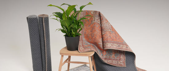 Washable rug hung on the back of a chair with a pot of plant on the seat and more rolled up washable rugs